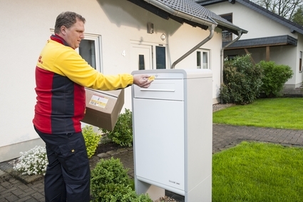 Zusteller vor Paketkasten